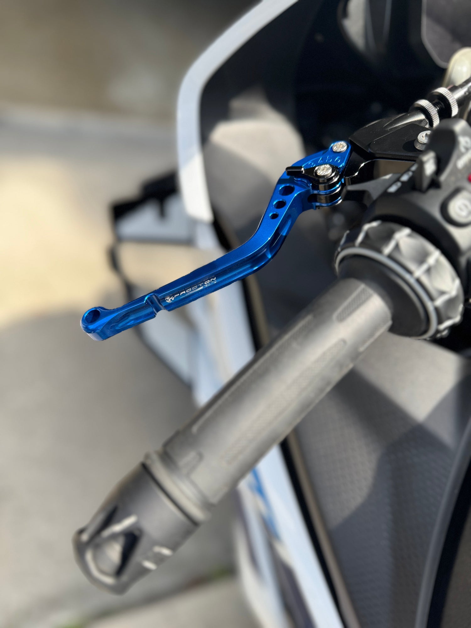 Close-up of a blue brake lever on a motorcycle handlebar.